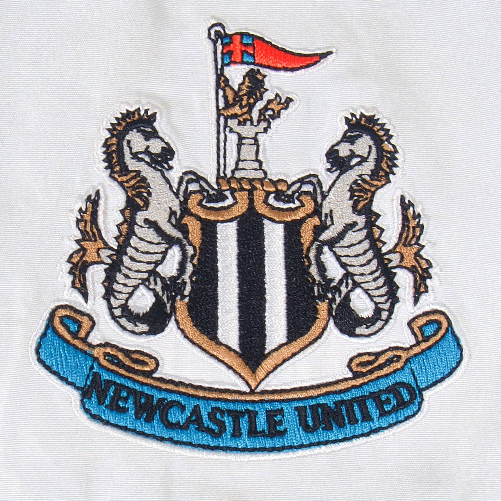 Newcastle Utd kids tracksuit in black with club crest to chest and left thigh