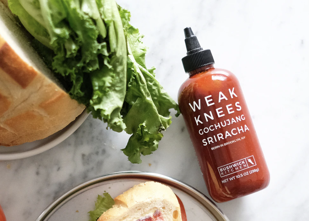 bottle of Weak Knees sriracha sauce with bread and lettuce