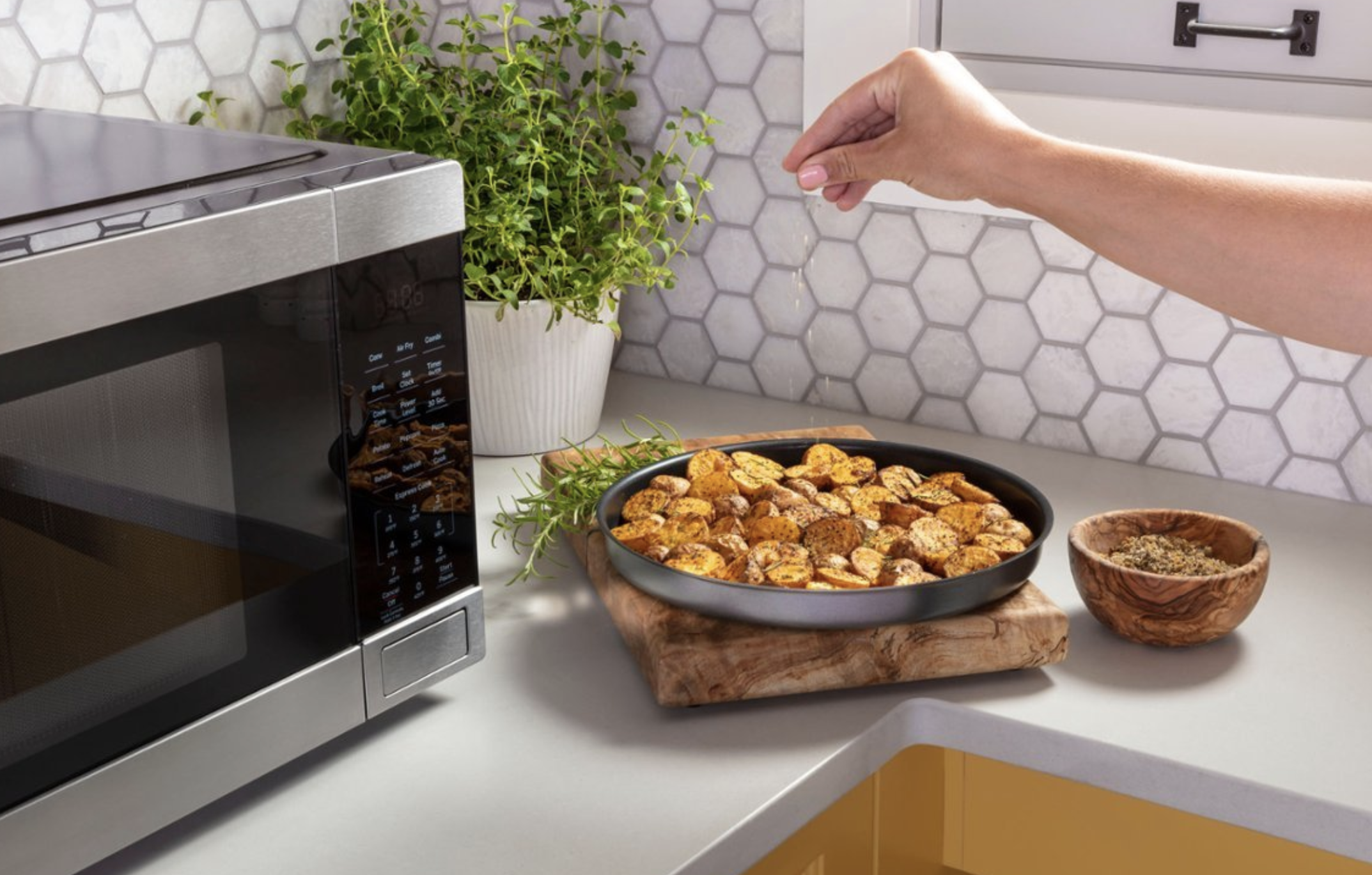 person sprinkling salt on fries next to microwave