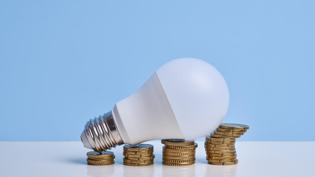 A white LED light bulb laying on ascending stacks of coins.