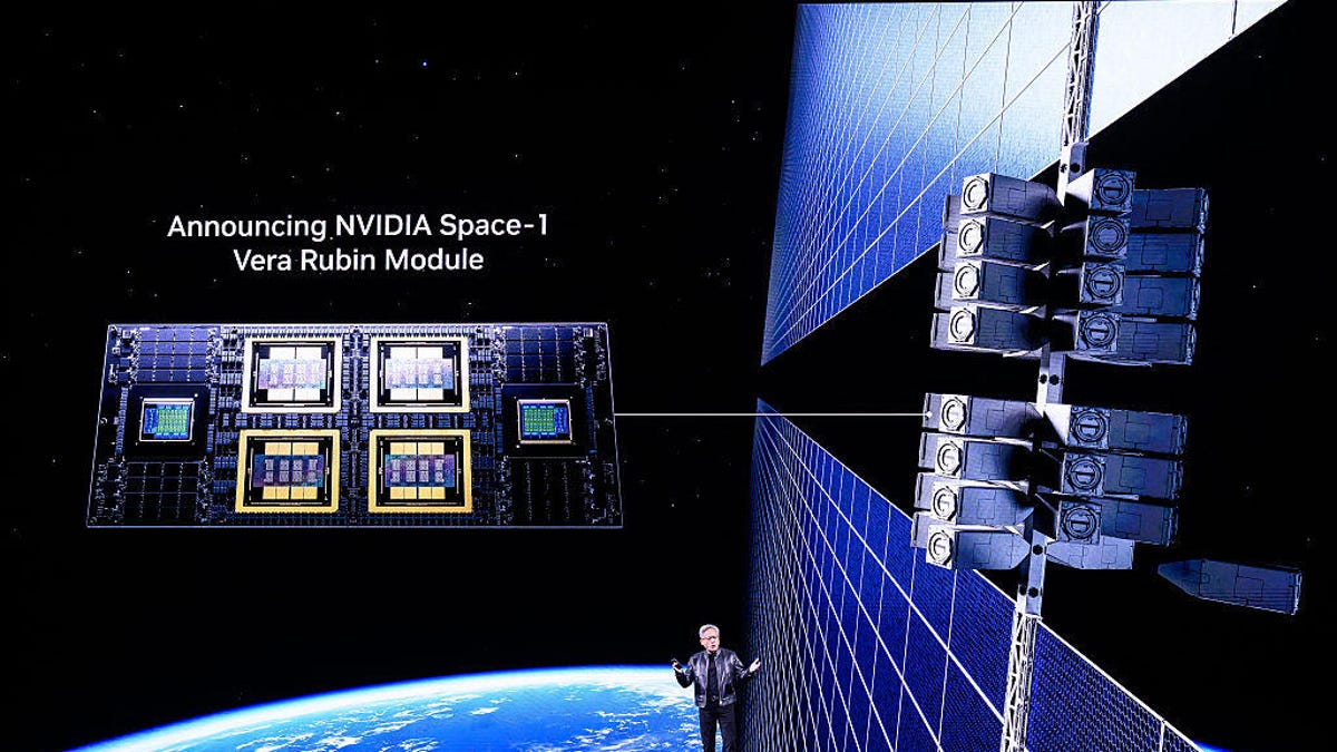 Jensen Huang stands in front of a large image with a computer chip and a satellite.