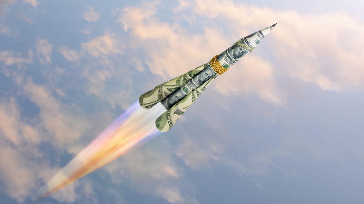 A rocket made of $100 bills flying through the sky.