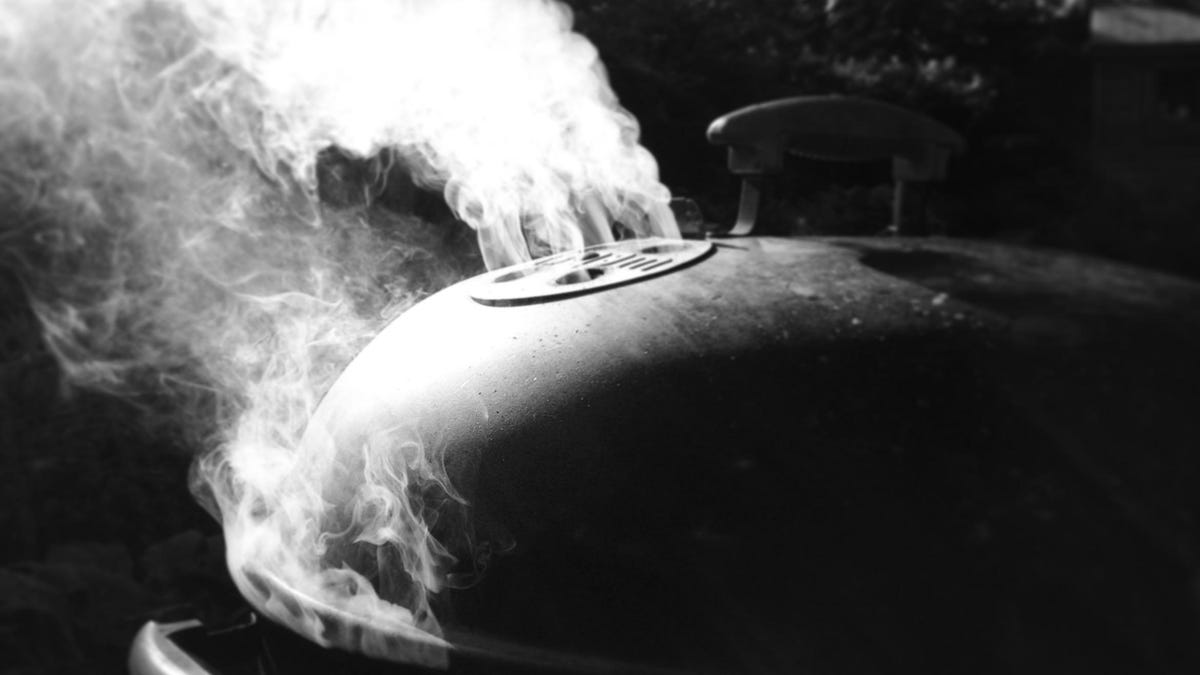 smoke pours from a Weber grill