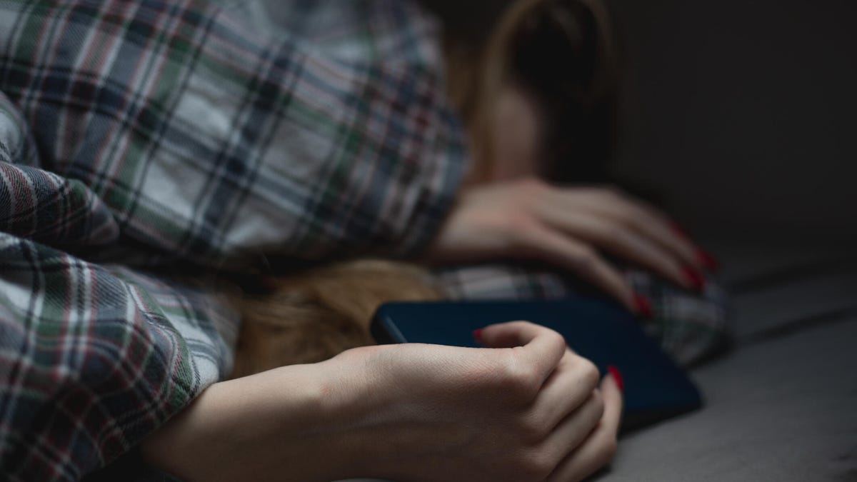 Unrecognizable teenage girl asleep with phone in her hand