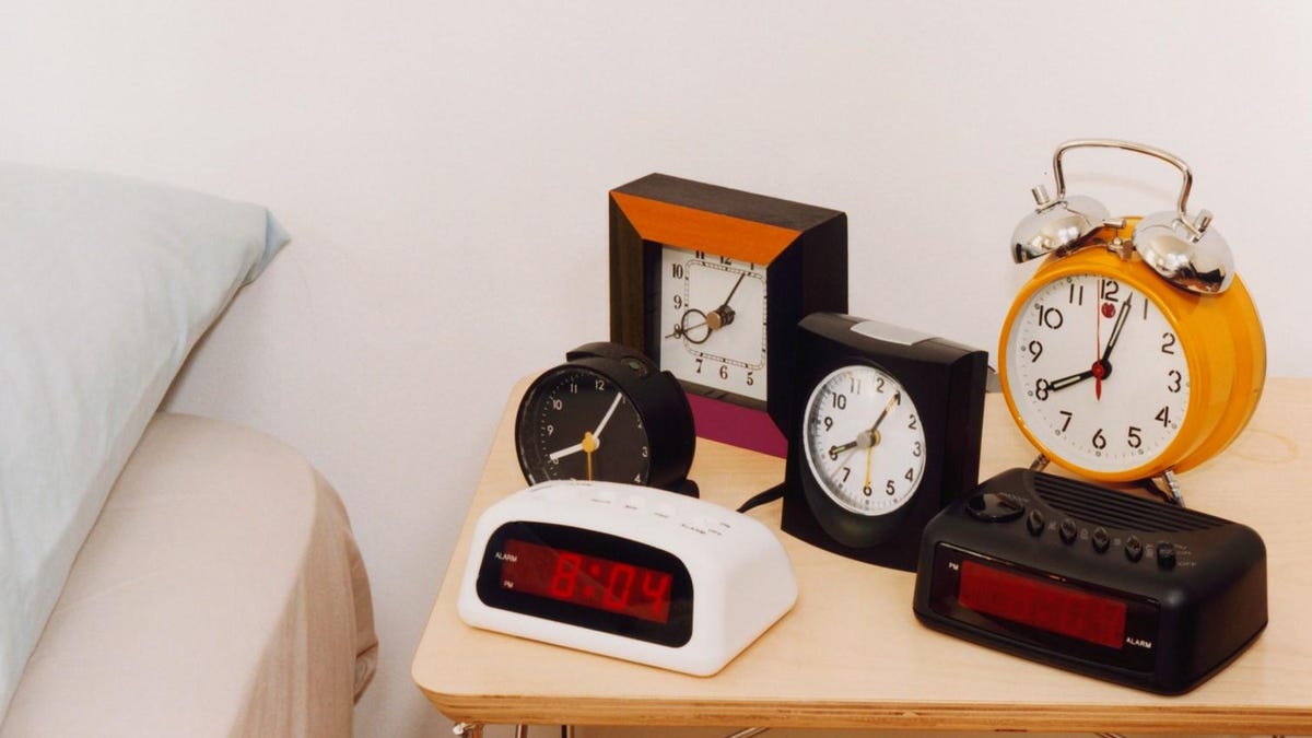 Six alarm clocks on a night table