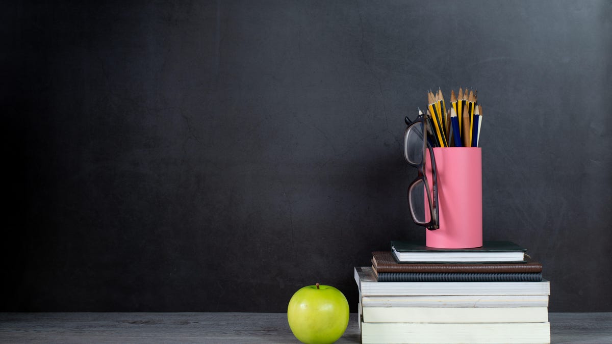 An image of a chalkboard, an apple, a stack of books, a pair of glasses and a tin of pencils gettyimages-1175290697
