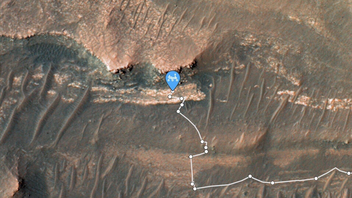 Orbital view of Jezero Crater and the "bacon strip," a lighter geologic formation across a darker area of river delta on Mars. A line shows the Perseverance rover's travel path.