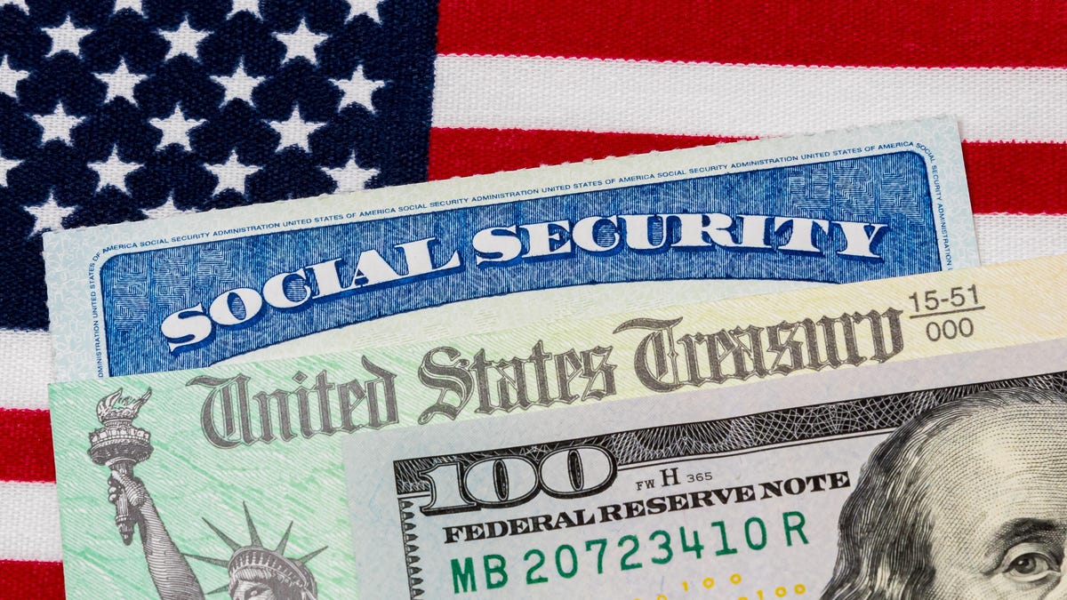 a $100 bill, US Treasury check, and Social Security card, all lined up on top of a US flag