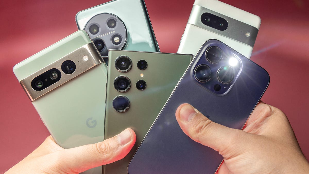 Many different phones in a person's hands.