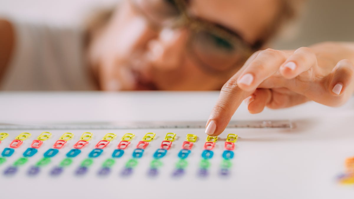 Woman placing paper clips in perfect lines.