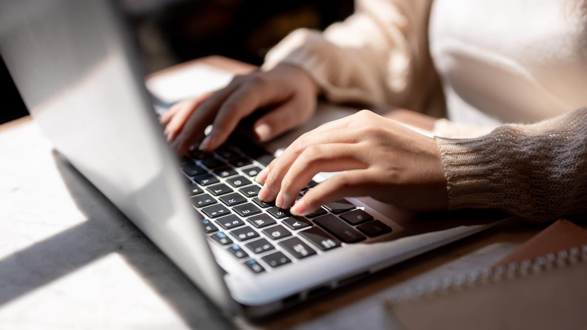 A close-up of a person typing on a laptop