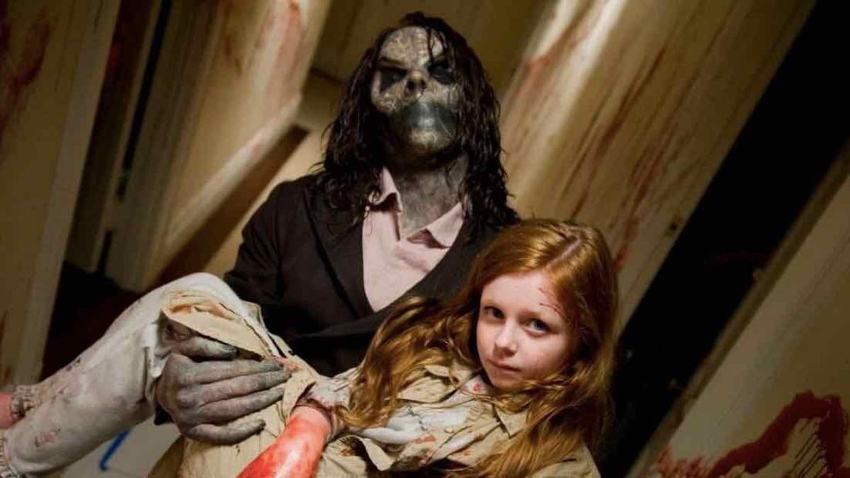 In a scene from the movie Sinister, a humanoid monster carries a young girl in its arms