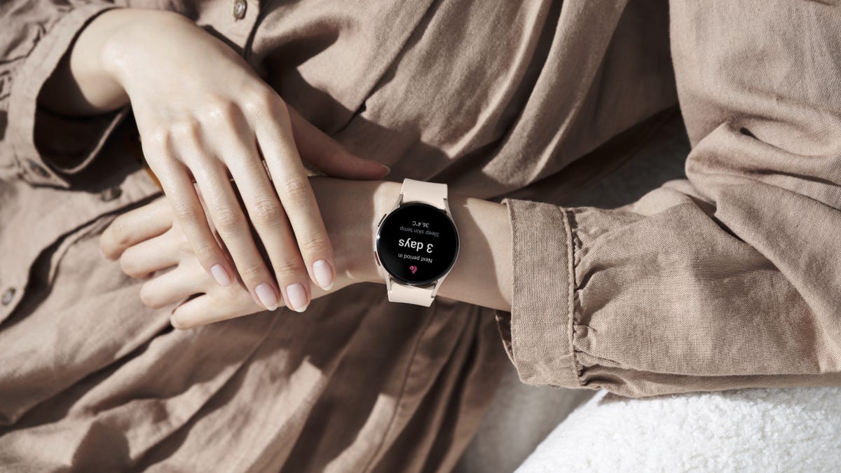 A woman in a tan coat wearing a smartwatch