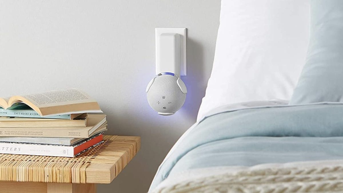 an Echo Dot plugged into an outlet bedside