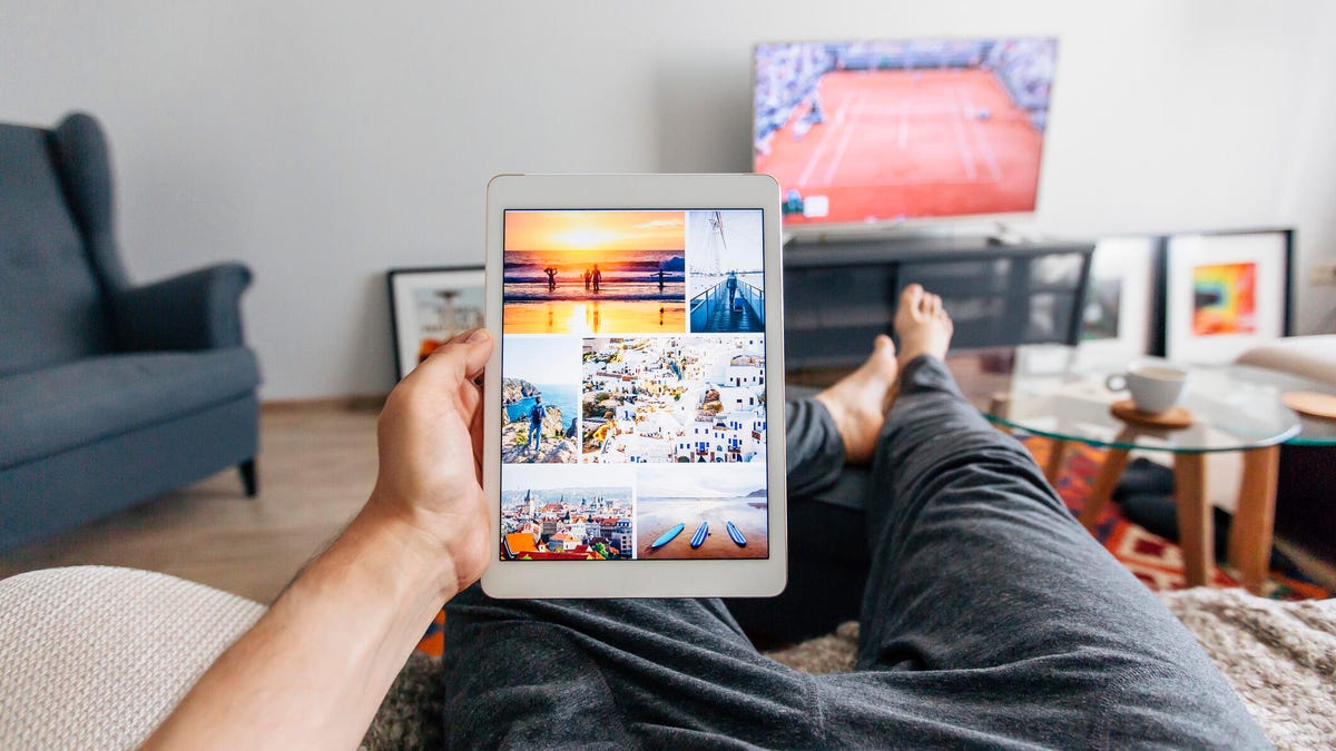 A man sitting on a couch holding a tablet