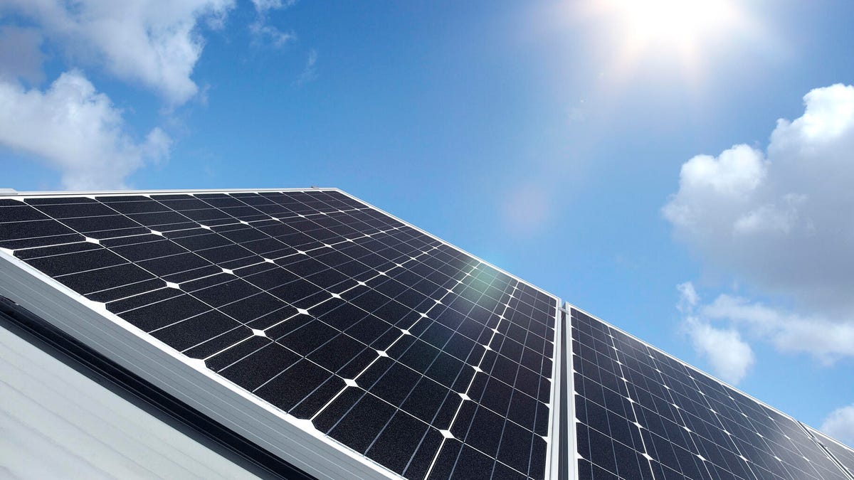 Rooftop solar panels with the sun overhead.