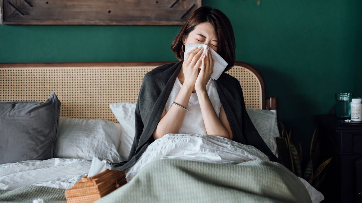 Woman with allergies sneezing in bed