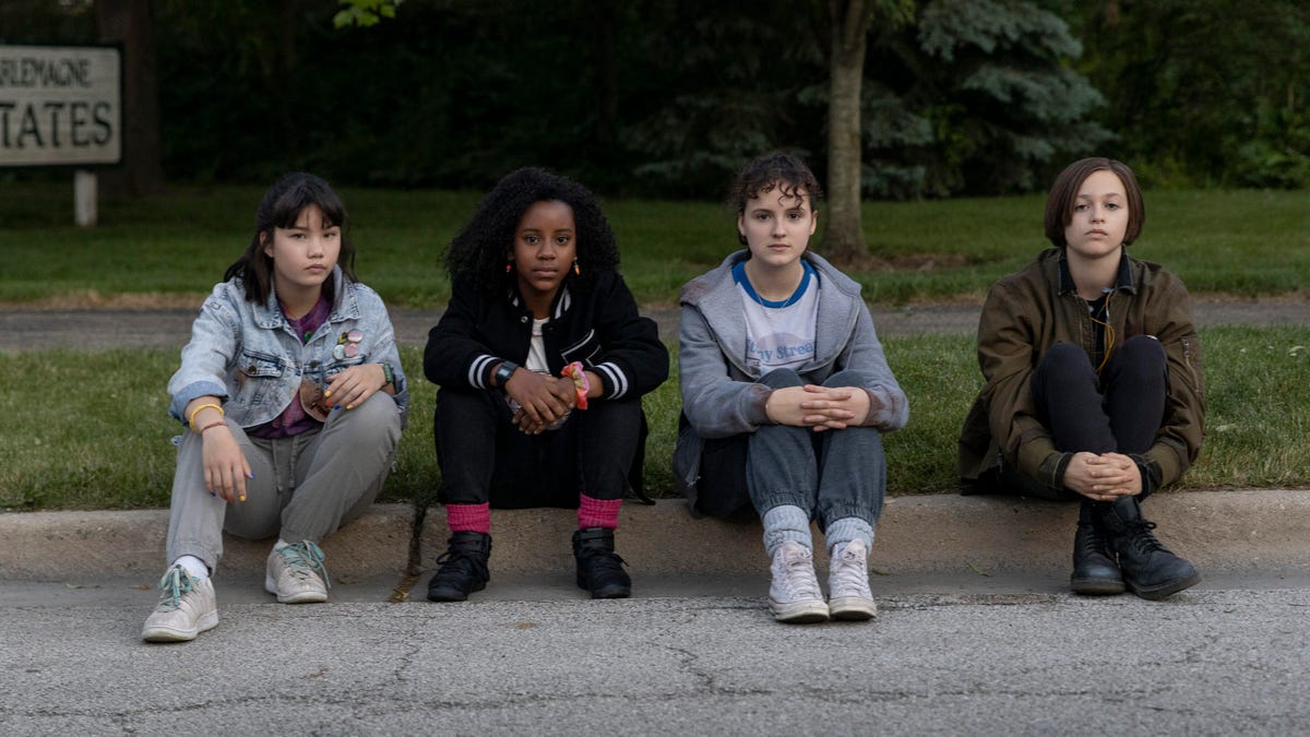 Four teenage girls sit on the kerb.