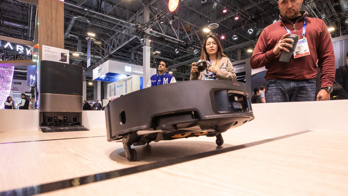 A round robot vacuum propped up as it approaches a ledge.