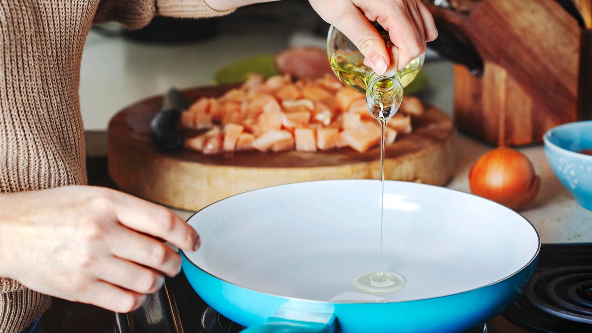 person pouring oil in ceramic skillet