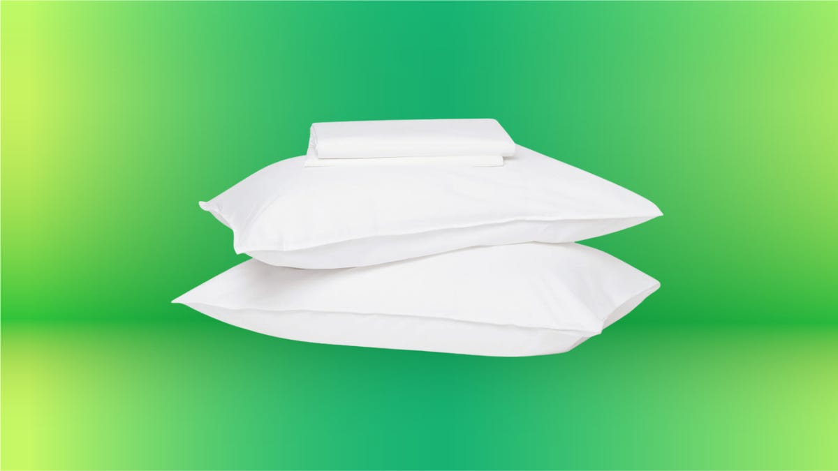 Two white pillows and two white pillow cases stacked on top of each other, set against a vibrant green background.