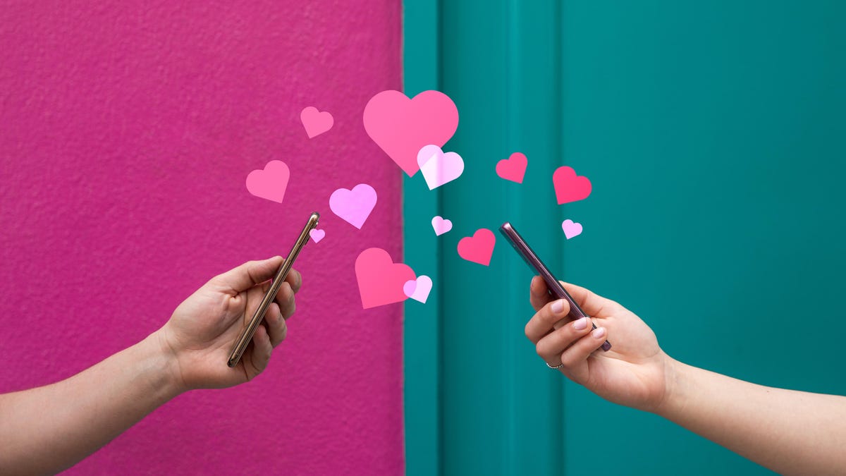 Hands holding phones toward each other, with hearts in between