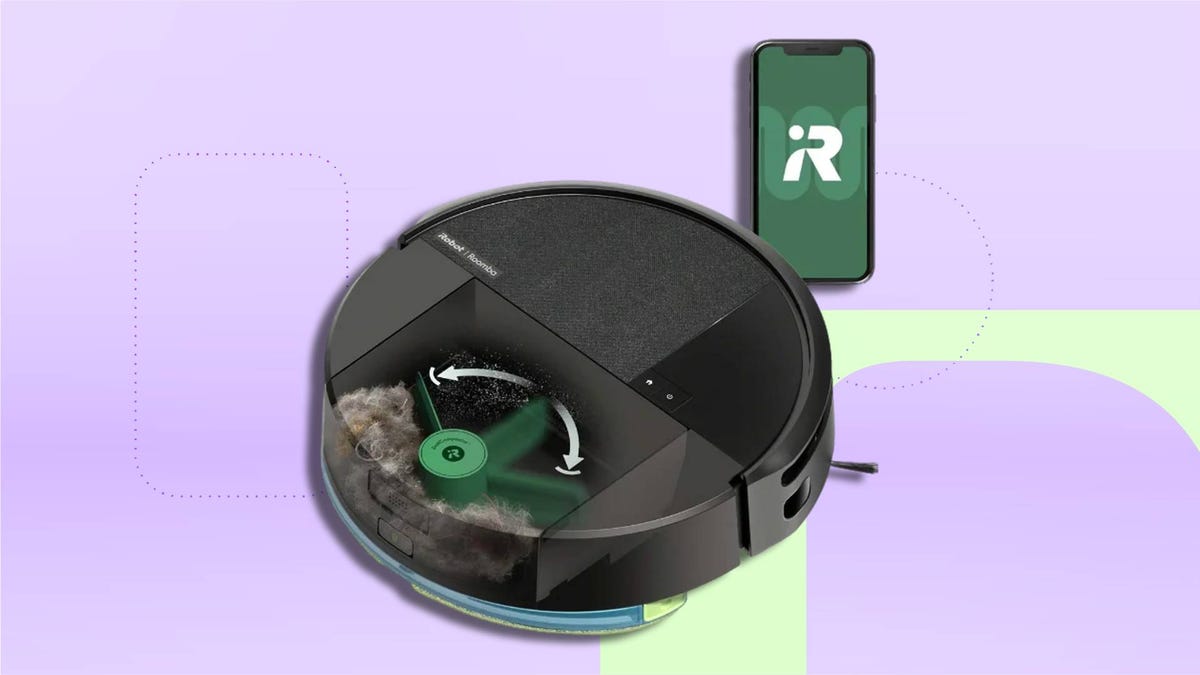 black robot vacuum showing its internal dust compactor crushing debris inside the bin, with a smartphone displaying the Roomba app on CNET background