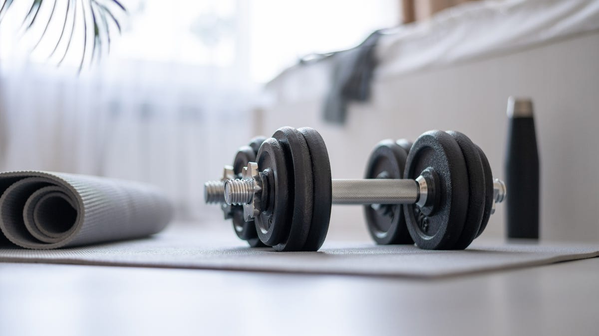 Dumbbells, mat, water, on the floor in the bedroom preparing for workout.