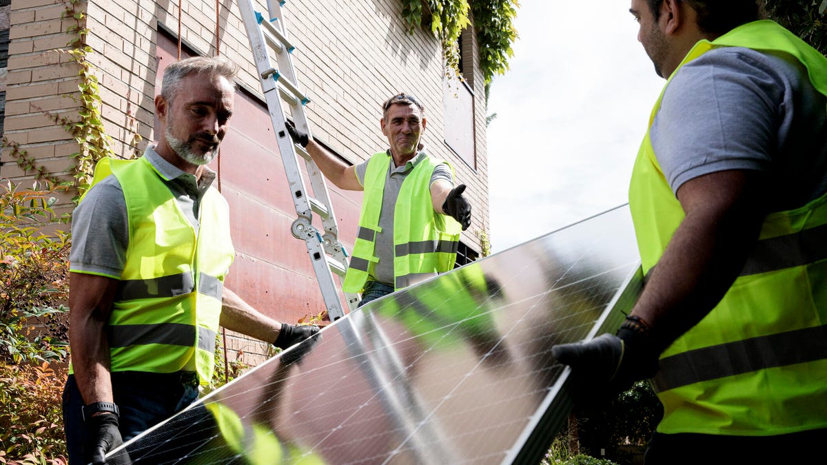 Three construction workers installing solar panels