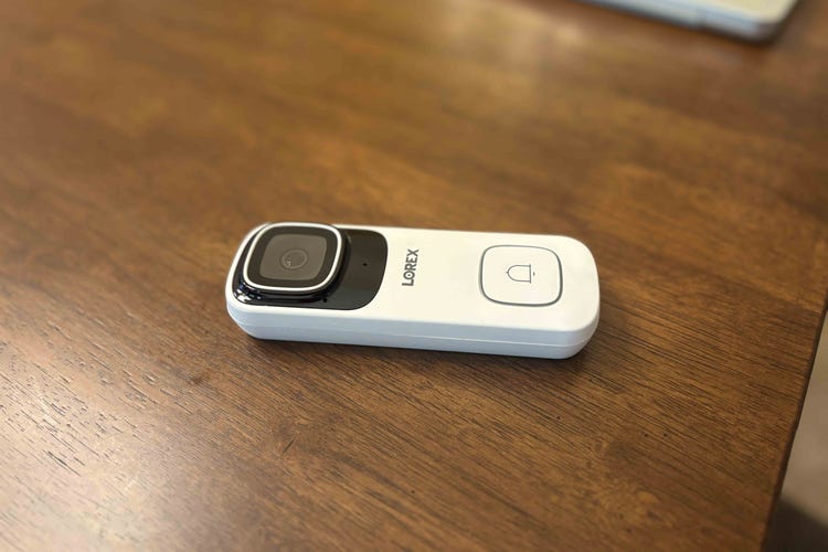 A Lorex white doorbell on a wooden table.
