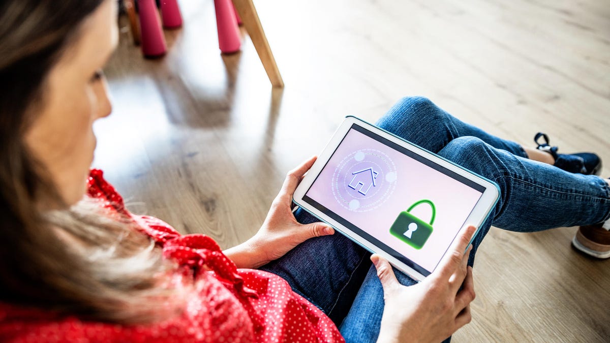 A woman sitting on the floor looking at a screen with home and lock icons.