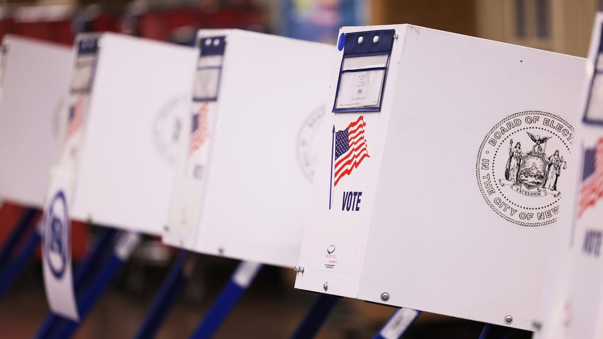 A line of white polling stations with American flags.