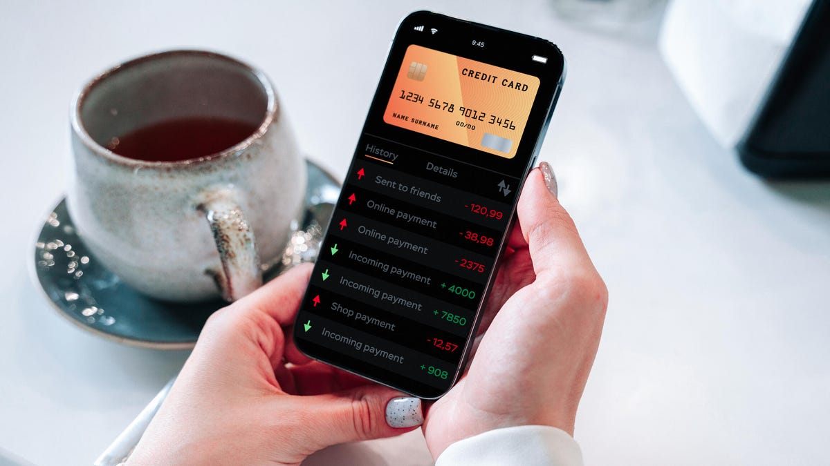 Smartphone user views credit card charges, with a cup of coffee in the background