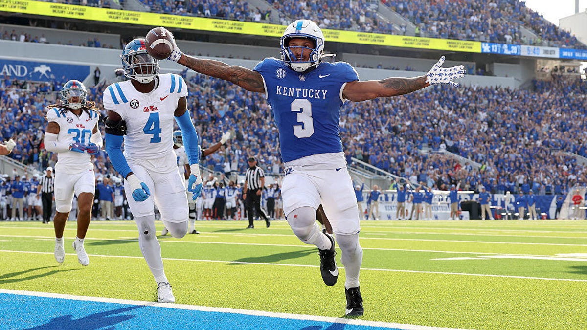 Football player Seth McGowan #3 of the Kentucky Wildcats, in dark blue, runs for a touchdown against the Ole Miss Rebels.