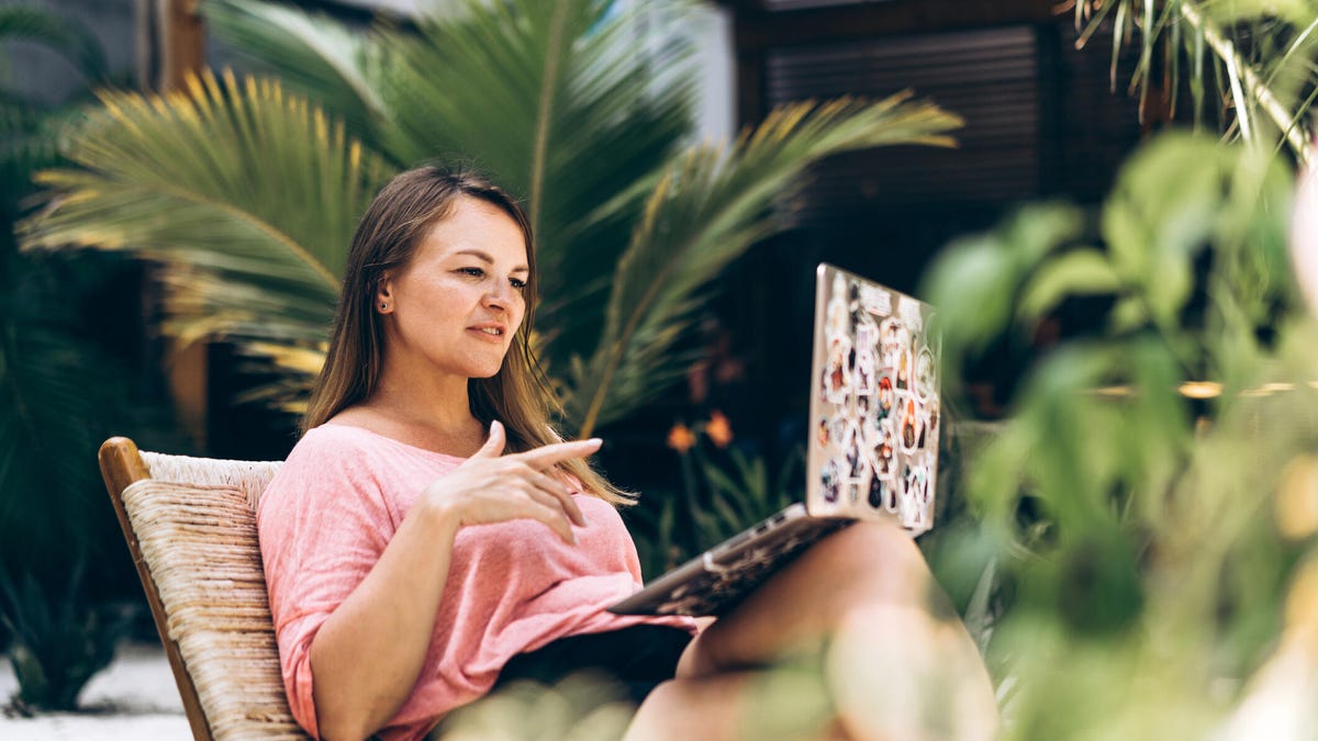 A student sits in a pool chair with a laptop, studying while on vacation