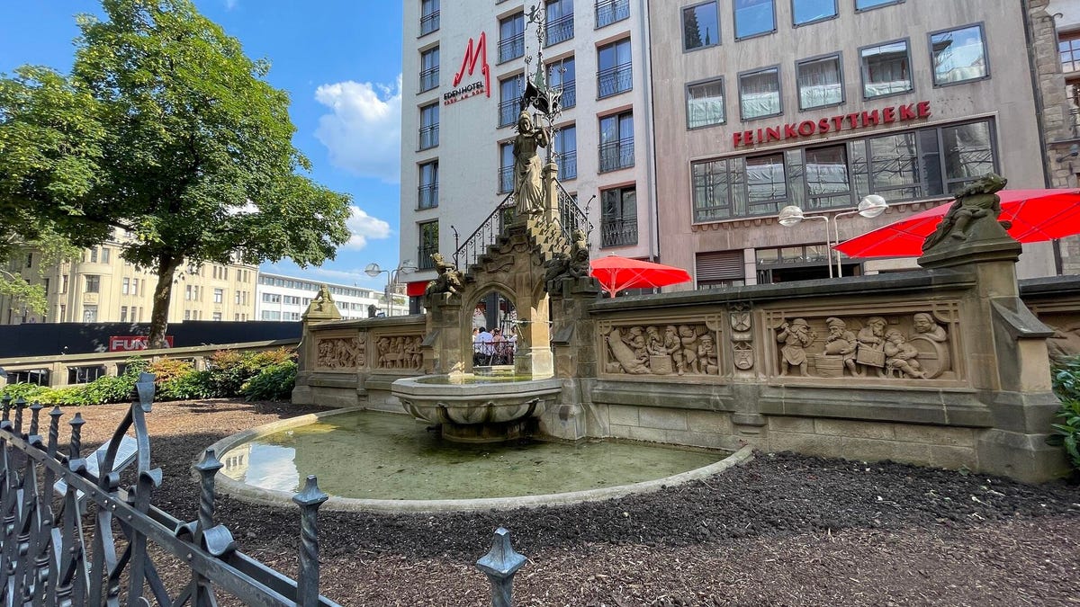 An old fountain with inscribed scenes of gnomes at work and people at leisure.