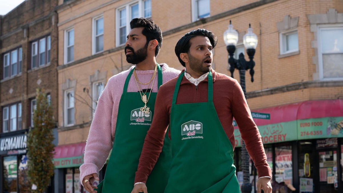 two men stand in the street wearing green aprons