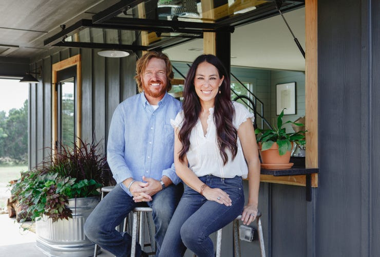 Chip and Joanna Gaines sitting outside of a house