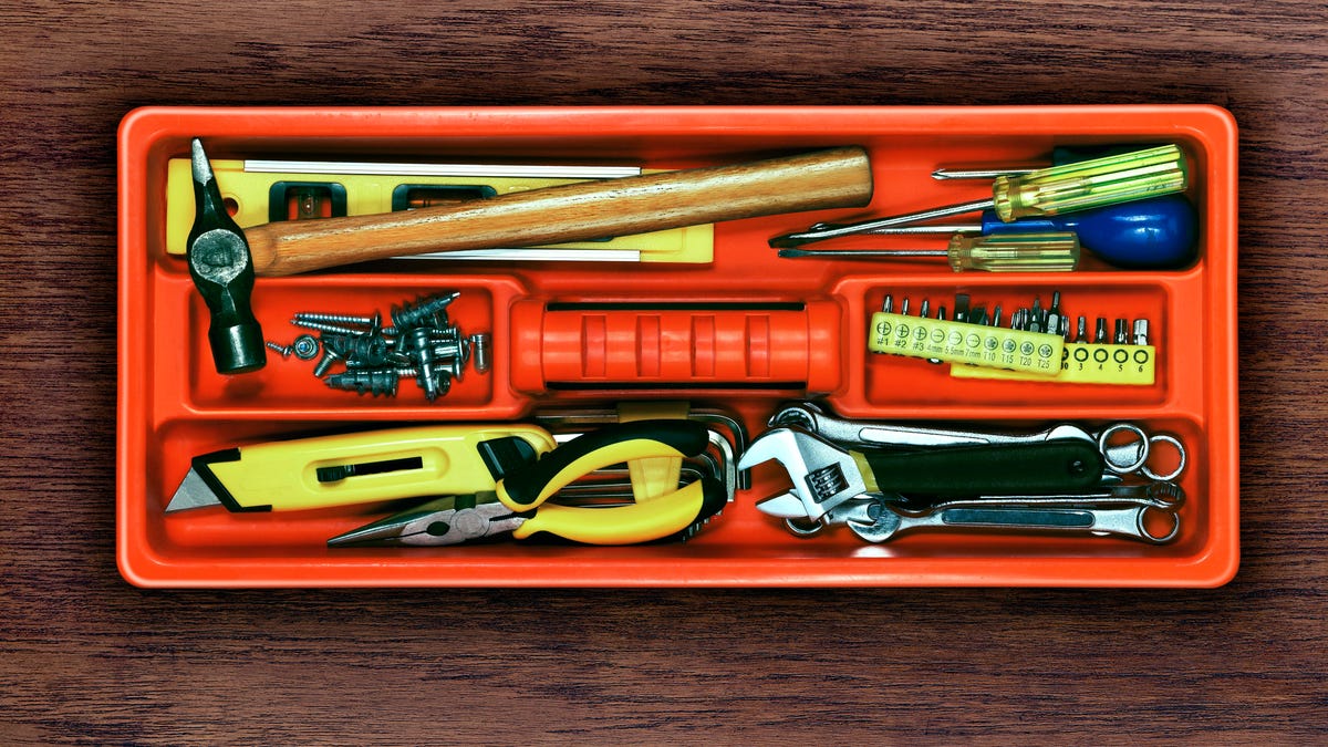 close-up of an essential toolkit for new homeowners: hammer, level, nails, screwdrivers, drill bit set, wrench set, box cutter and needle nose pliers