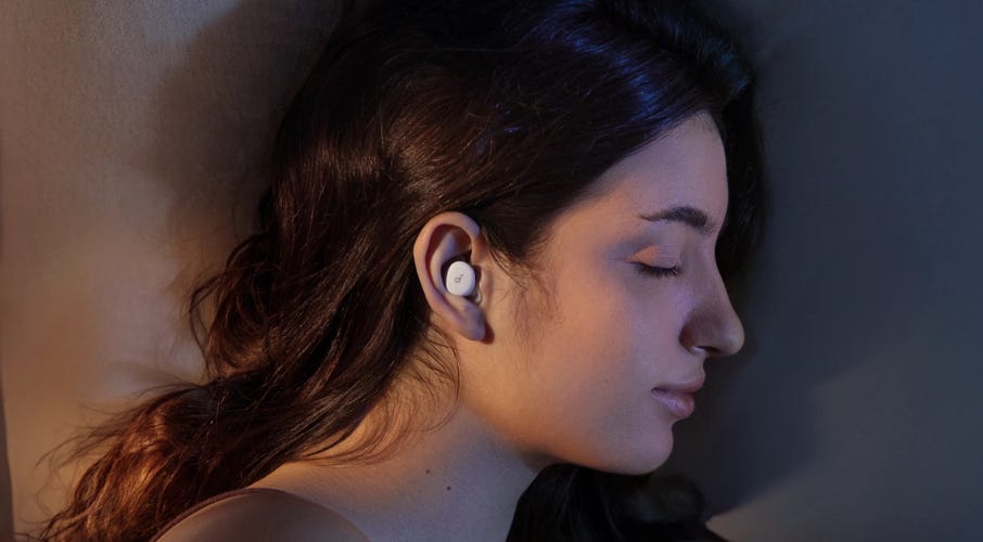 A person with brown hair sleeping on their side wearing a white Soundcore Sleep A30 Special earbud.