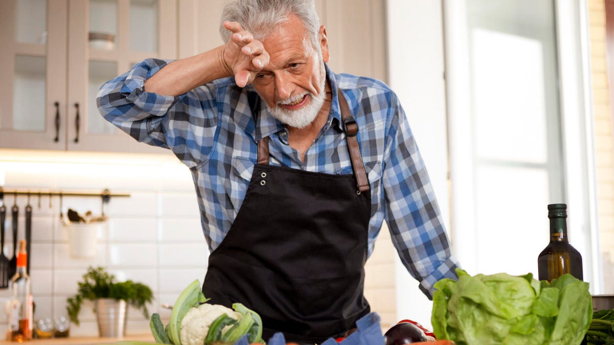 Man wipes brow and sweats while cooking