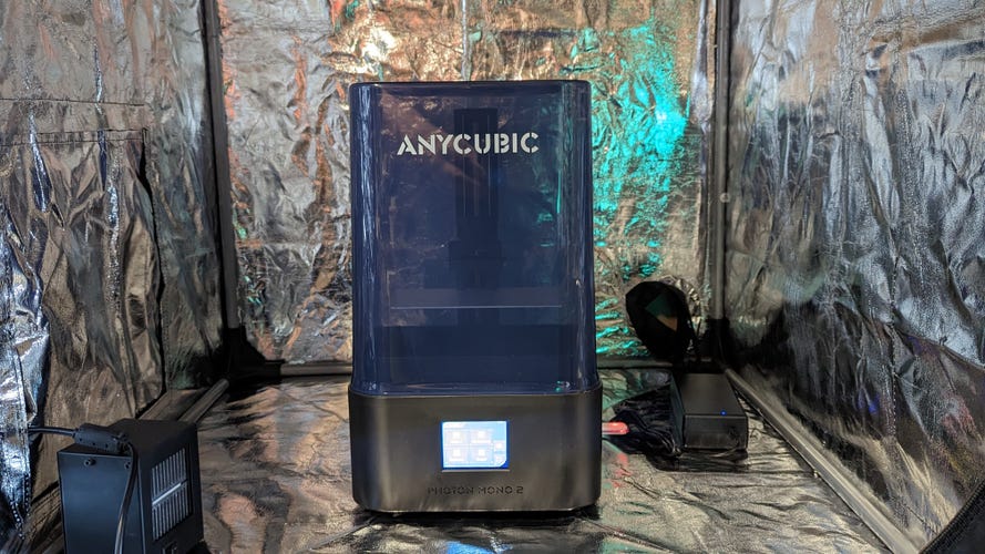 A blue resin 3d printer in a silver enclosure