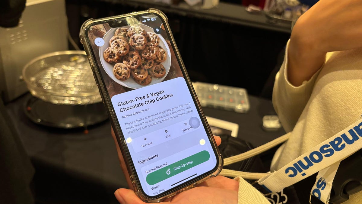 A person's hand holds a phone with a recipe on it in an app.