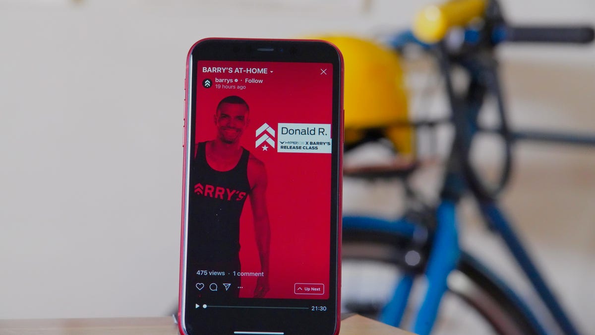 red iphone propped up on desk with a screen showing a workout video