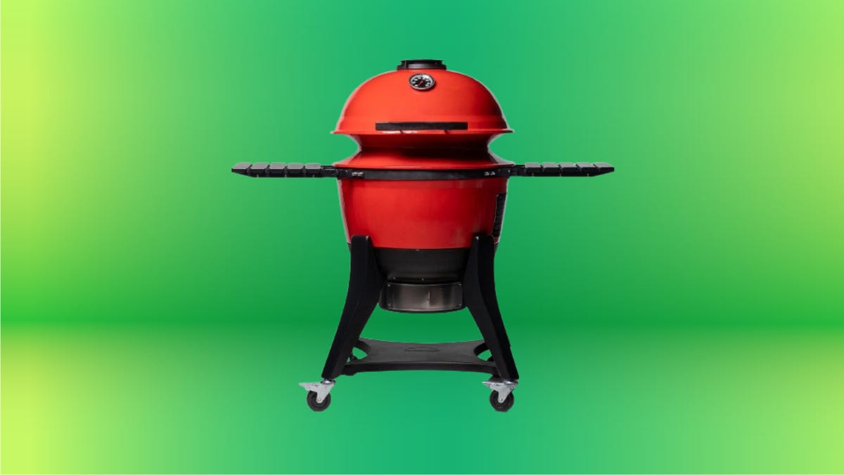 Red orange grill with black accents and grey/black wheels against green gradient background.