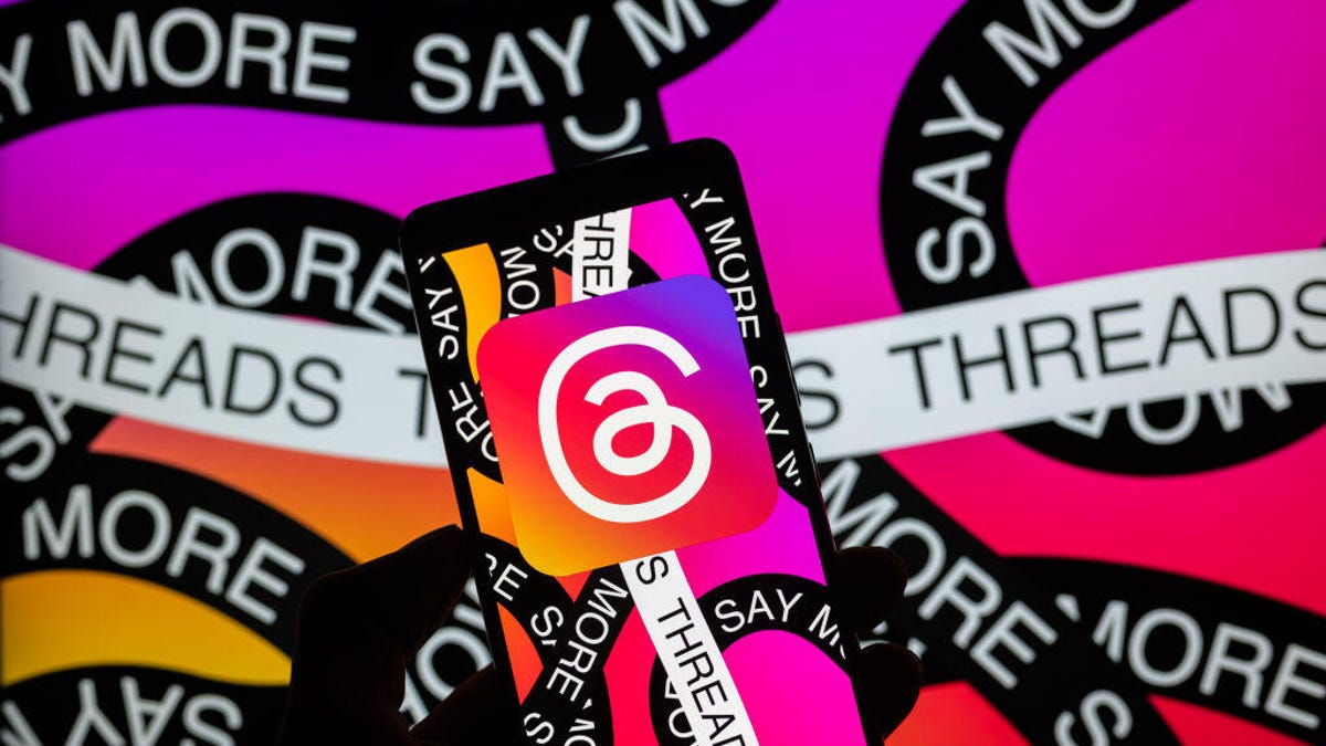 Threads logo on smartphone with pink and purple background