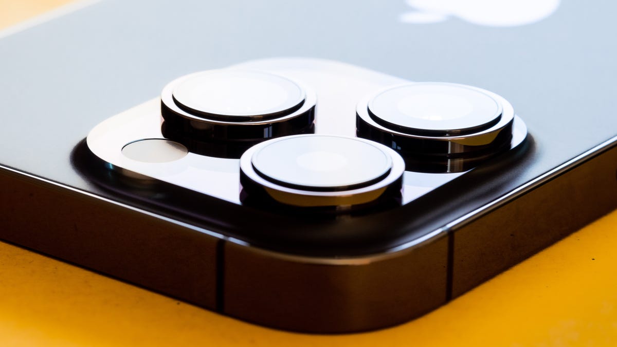 The three rear cameras of a deep purple iPhone 14 Pro point upward