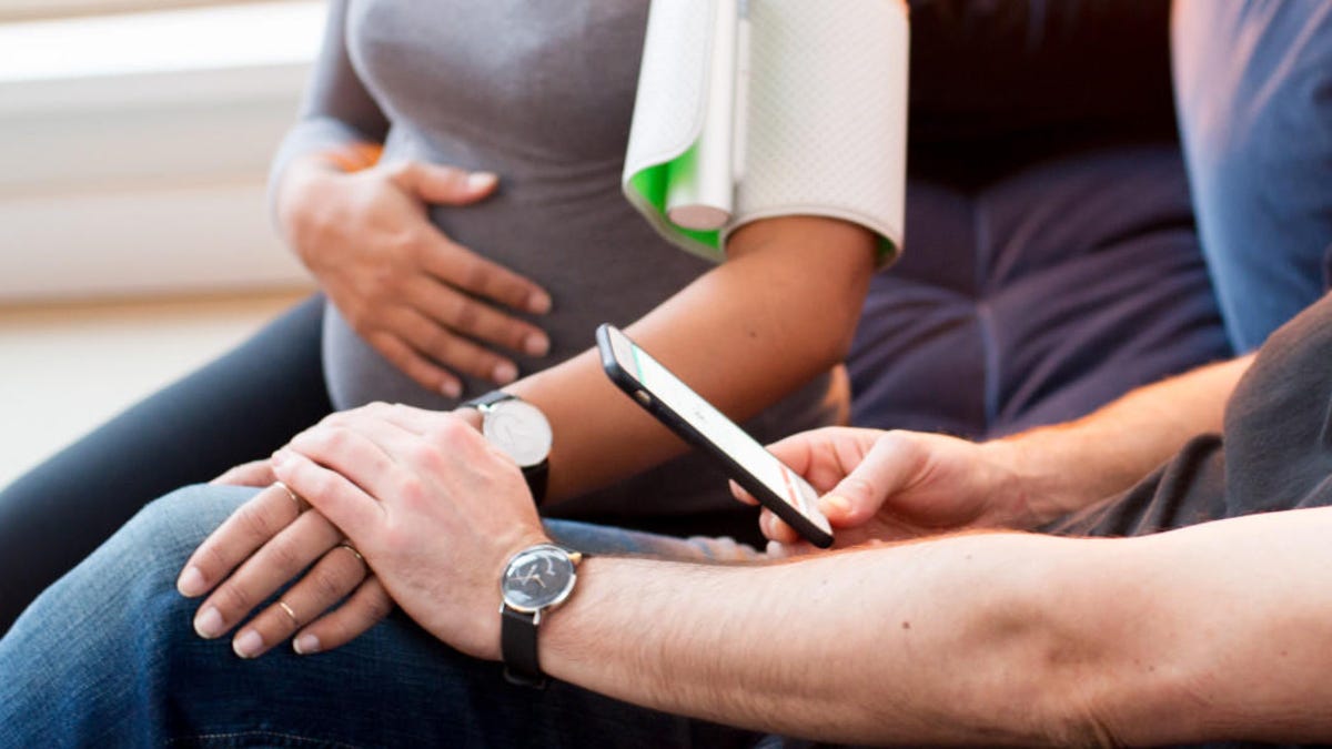 Pregnant woman takes her blood pressure at home.