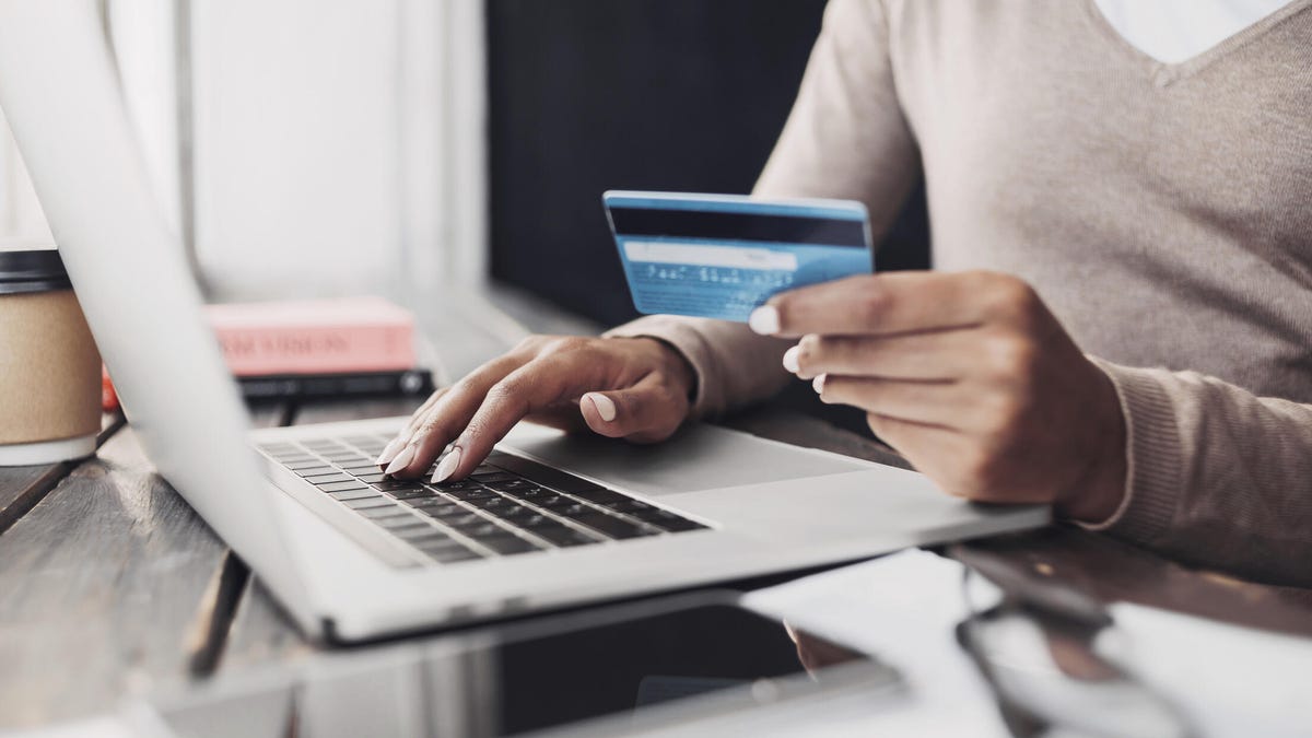 Girl using laptop computer and credit card at home.