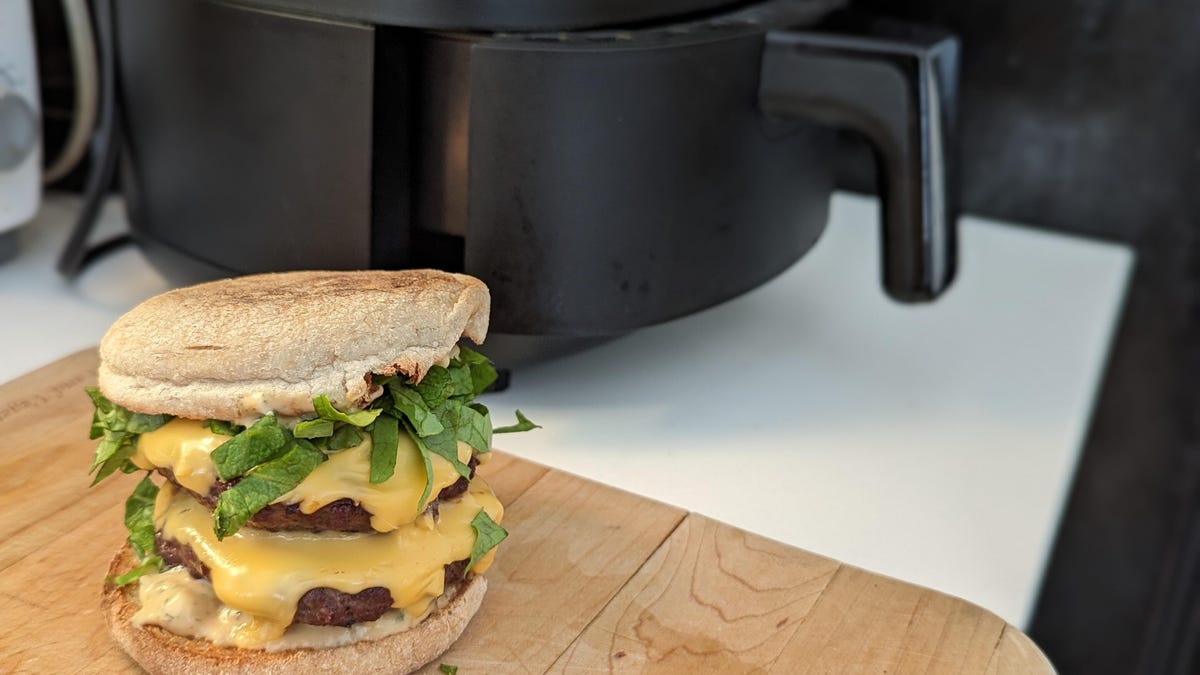 a tempting double patty cheeseburger sits next to an air fryer